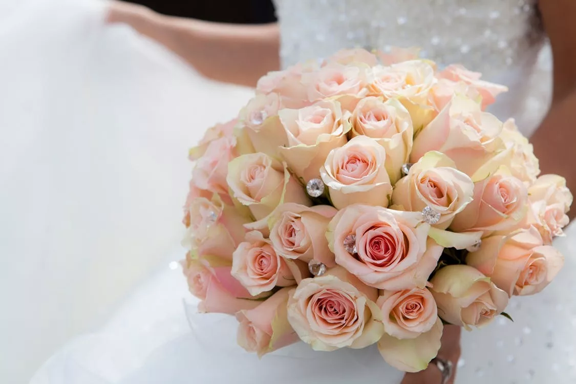 Bouquet de mariée en roses roses poudrées tenu par la mariée
