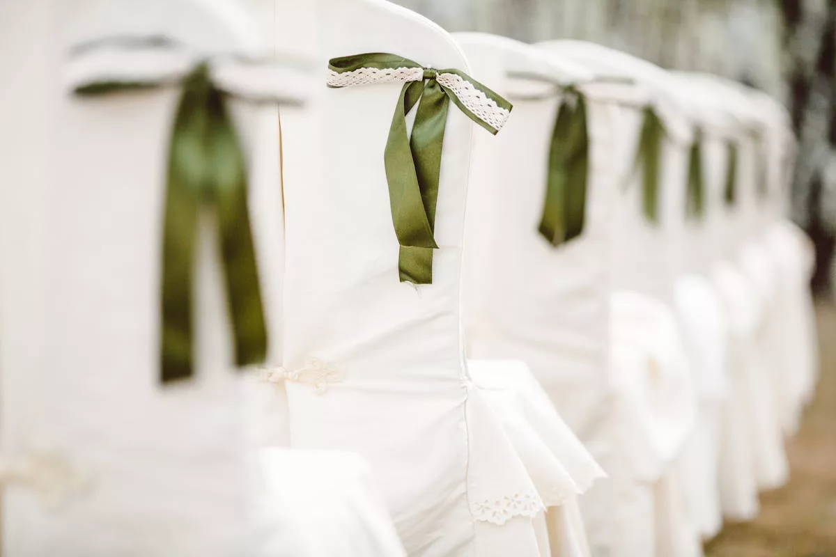 Chaises de mariage habillées de housses blanches et de rubans en satin vert sauge