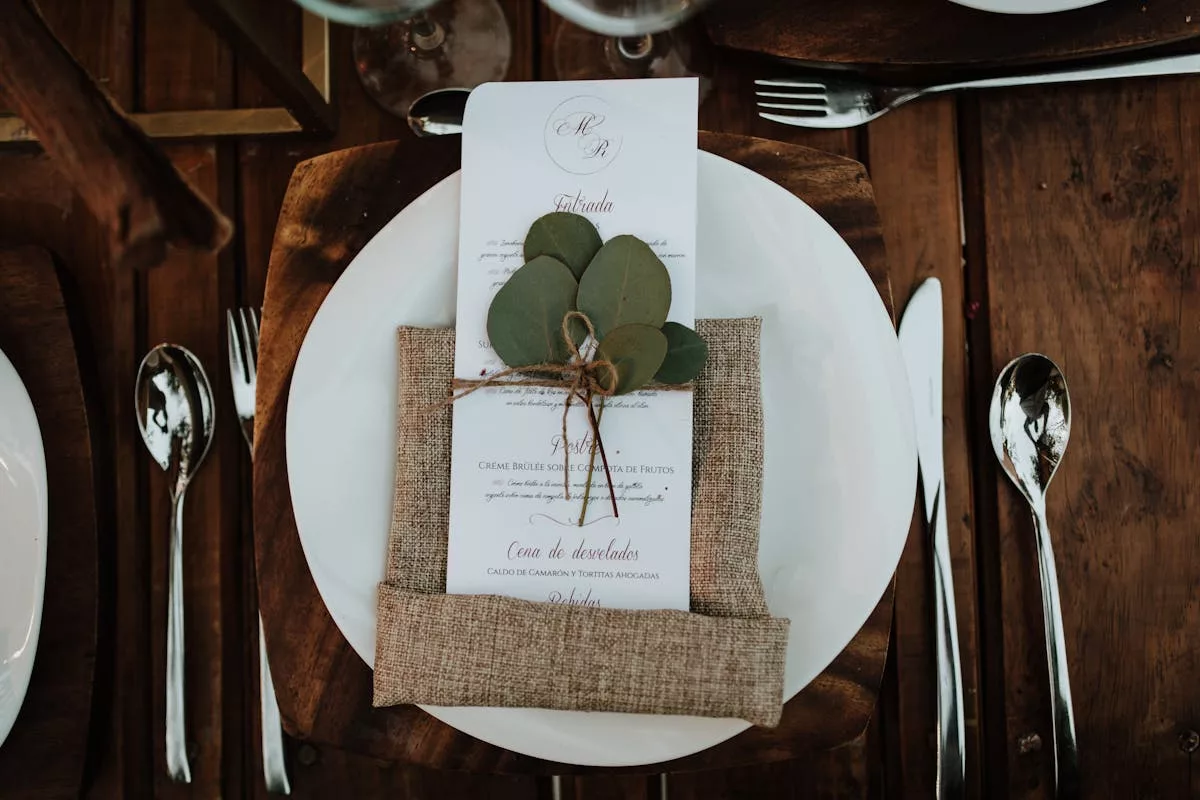 Menu de mariage avec branche d'eucalyptus posé sur assiette blanche et serviette en lin