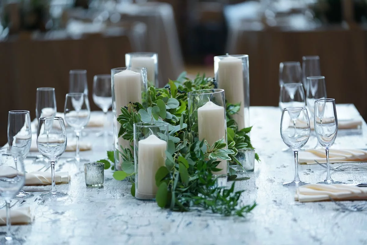 Centre de table mariage avec chemin d'eucalyptus, bougies blanches et verres en cristal
