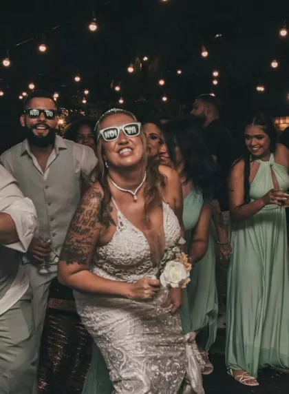 Mariée et invités qui dansent sous les guirlandes lumineuses pendant la soirée dansante