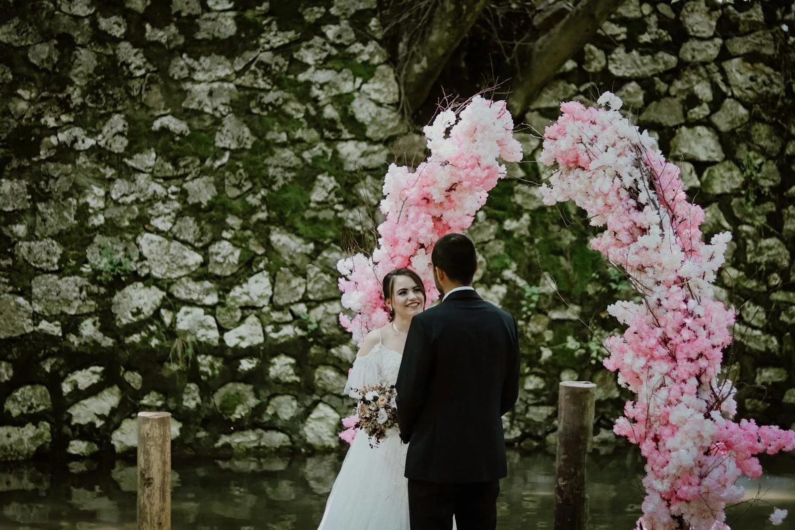 Couple devant une arche de mariage ronde fleurie de roses
