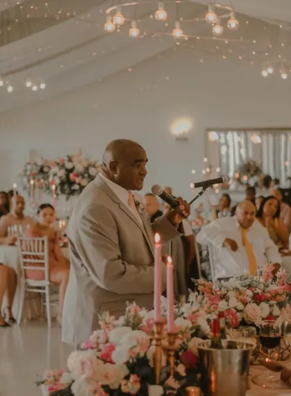 Témoin prononçant un discours de mariage au micro dans une salle romantique