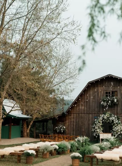 Mariage champêtre : cérémonie extérieure devant une grange en bois avec guirlandes lumineuses
