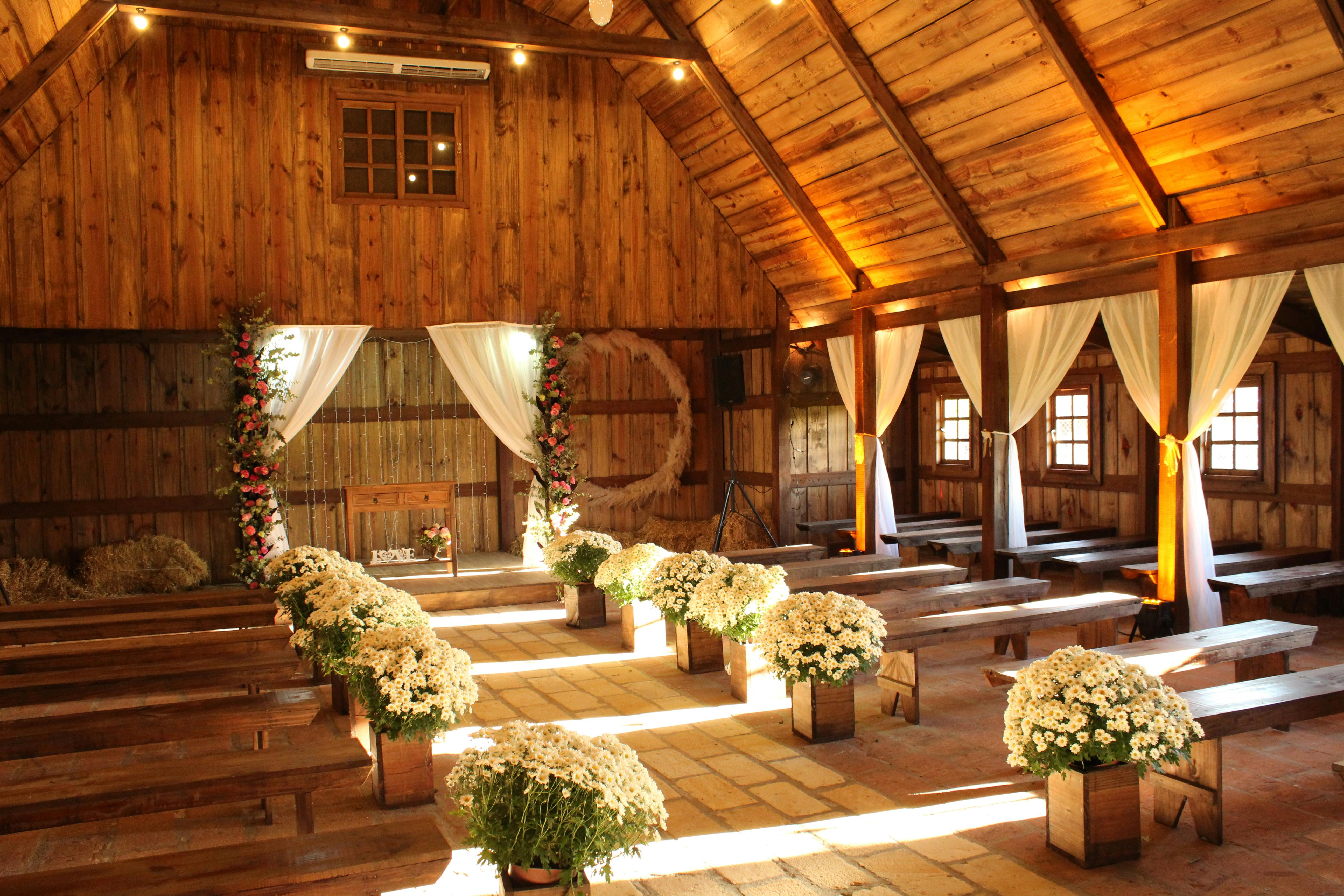 Intérieur de grange en bois décoré pour une cérémonie de mariage avec marguerites et tentures blanches