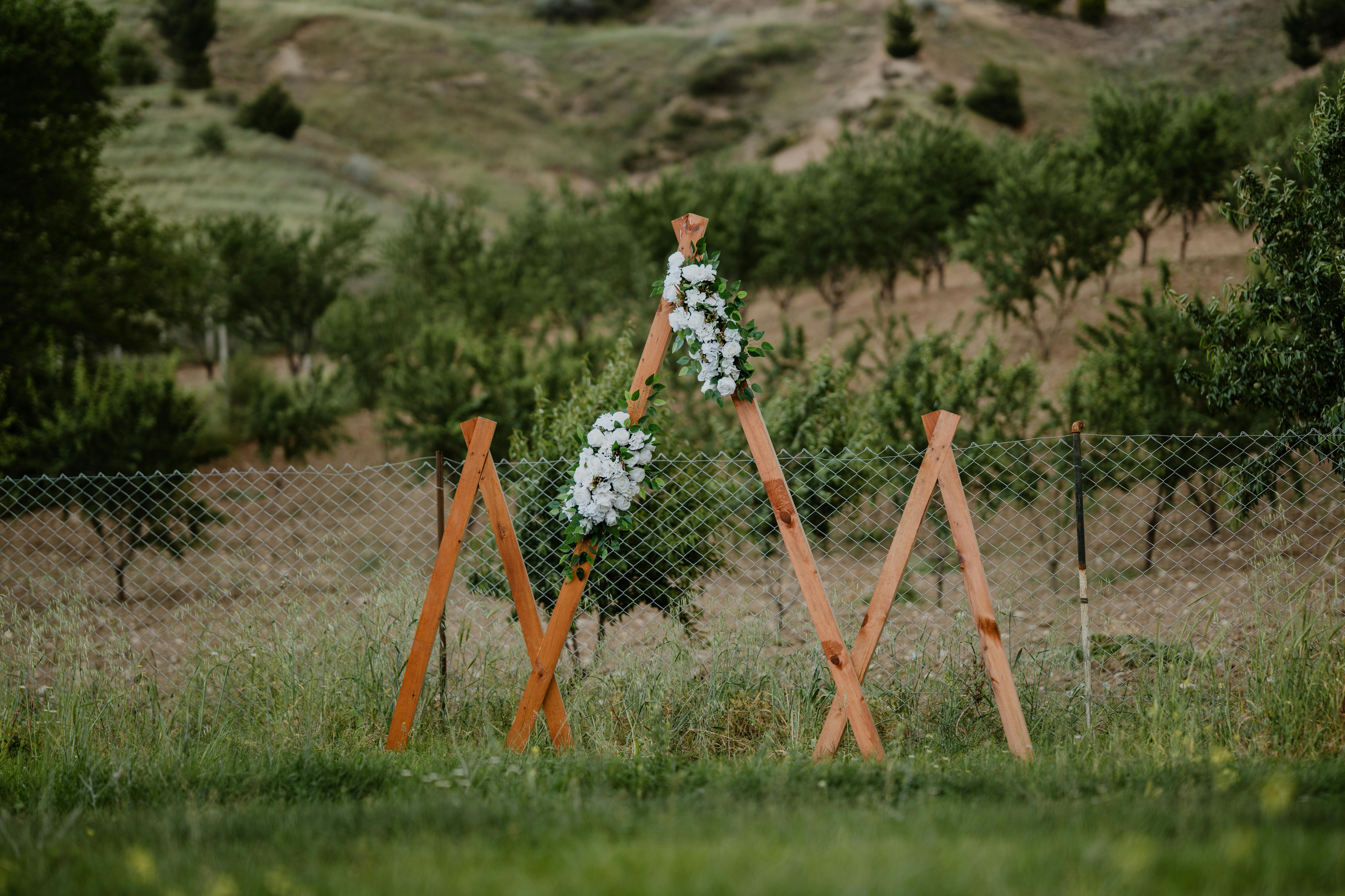 Arche de mariage en bois avec compositions florales blanches en pleine nature