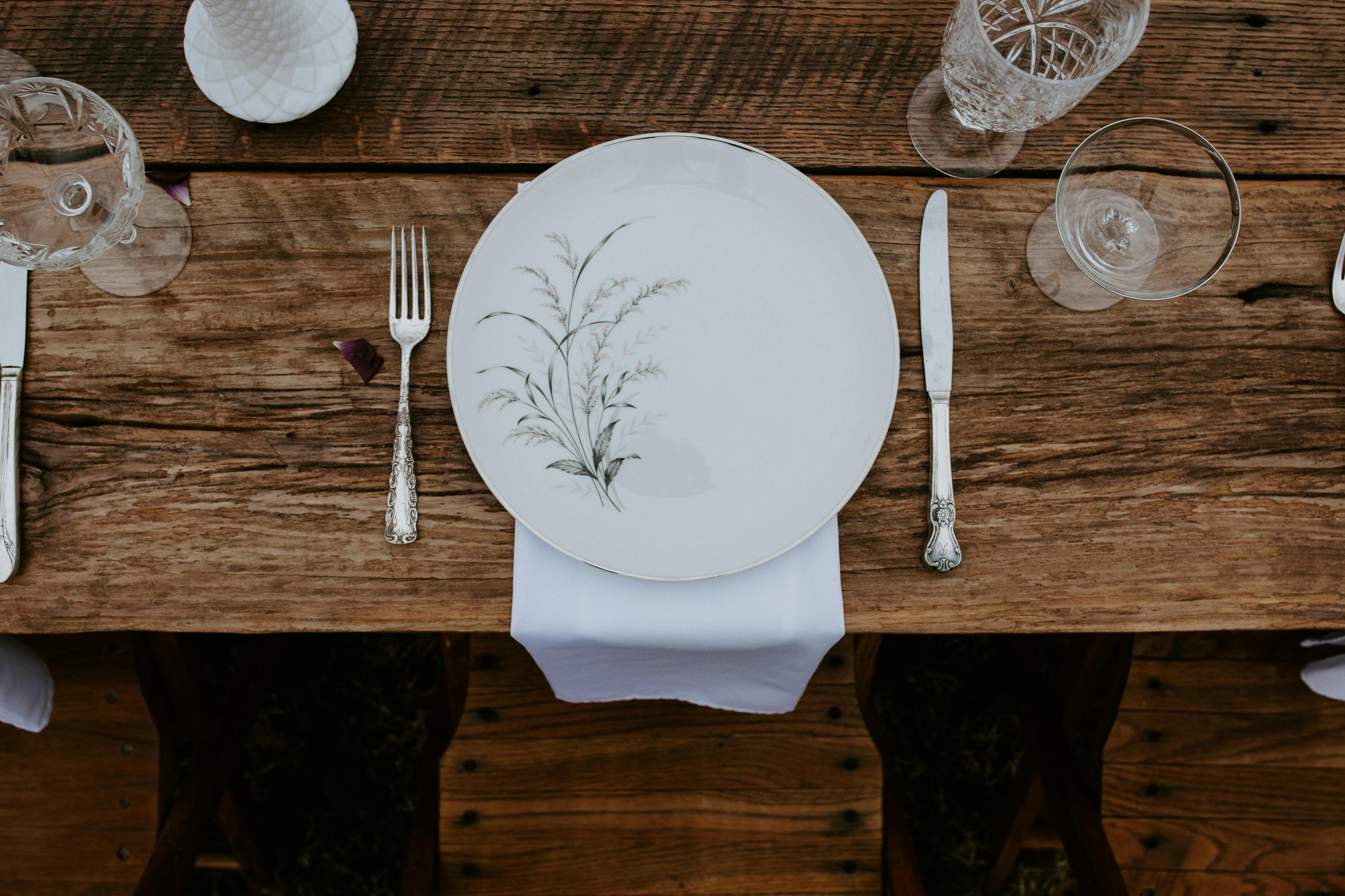 Table de mariage champêtre avec assiette à motif végétal, couverts en argent et nappe en lin