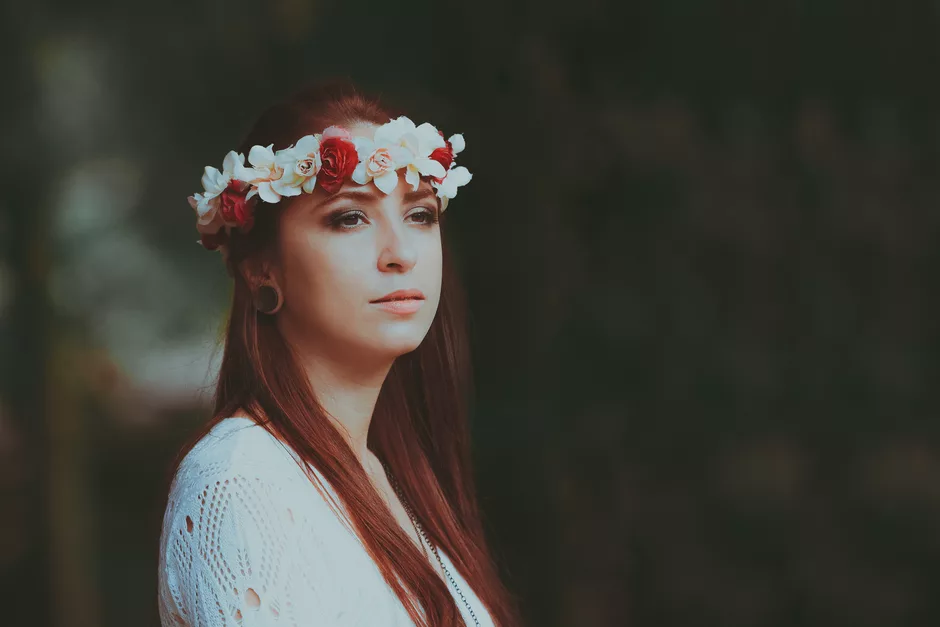 Portrait d'une jeune femme aux cheveux roux portant une couronne de roses blanches et rouges