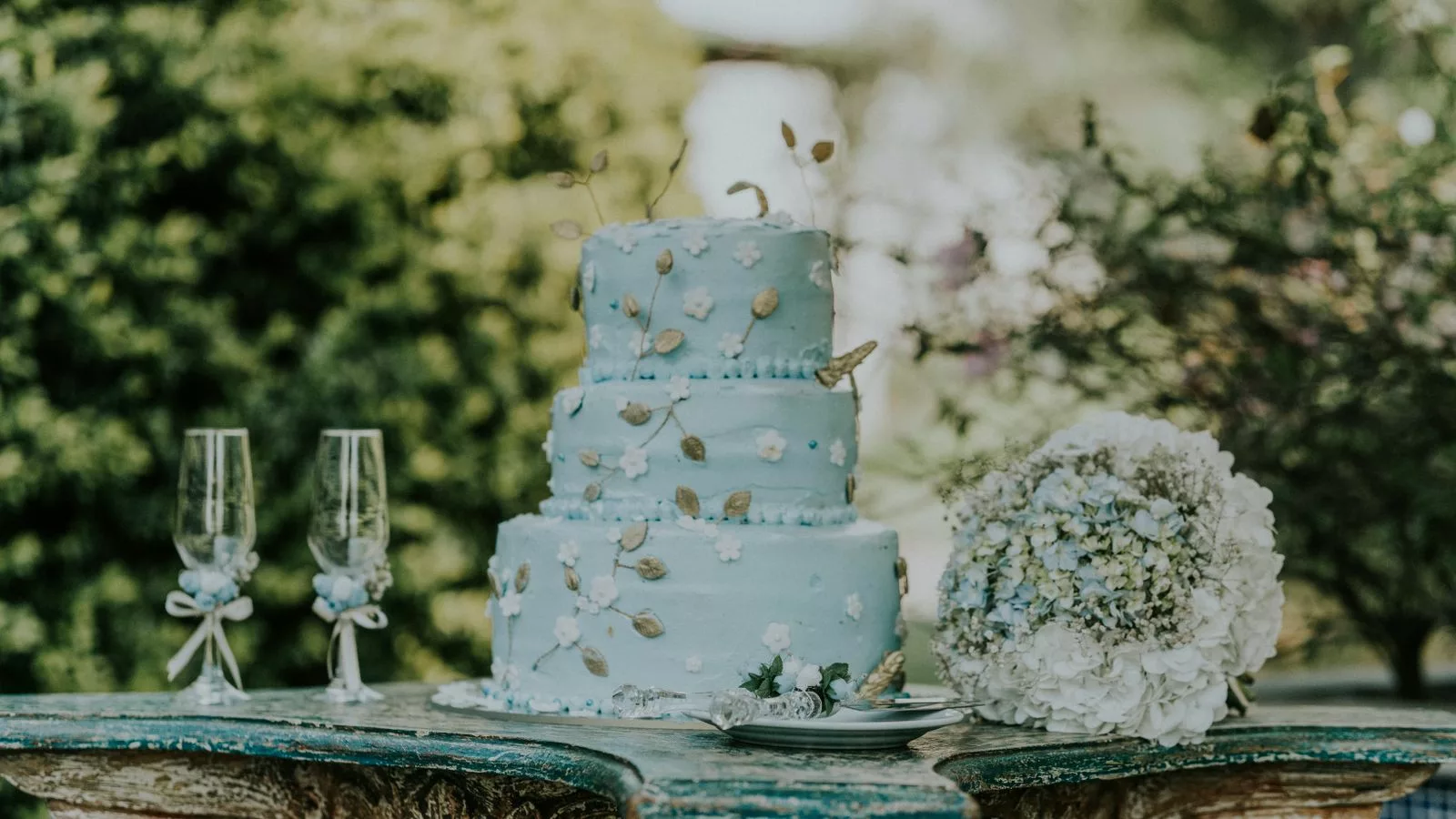 Pièce montée mariage bleu pastel avec fleurs blanches et accents dorés