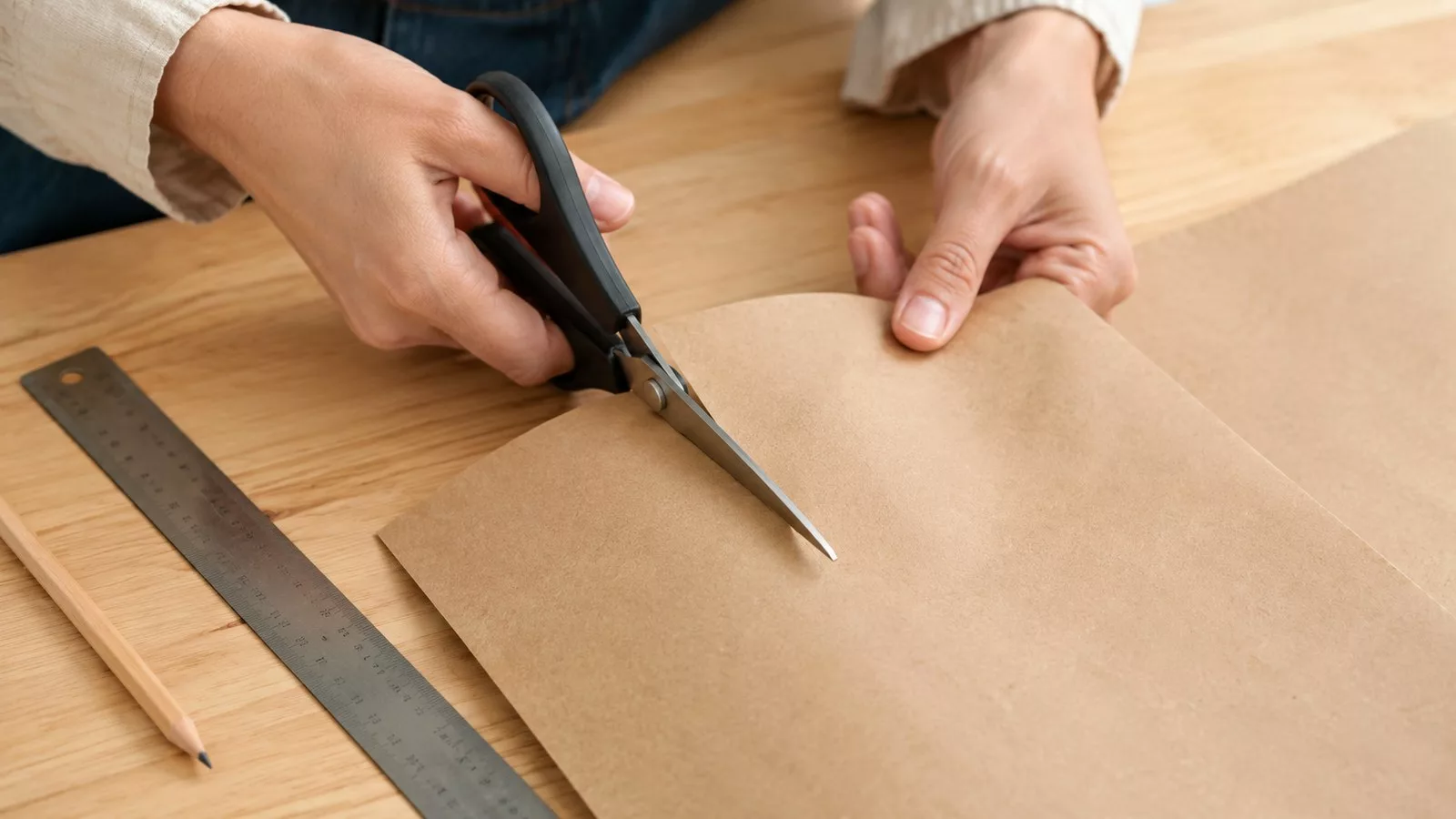 Découper la feuille de papier kraft brun avec une paire de ciseaux et une règle