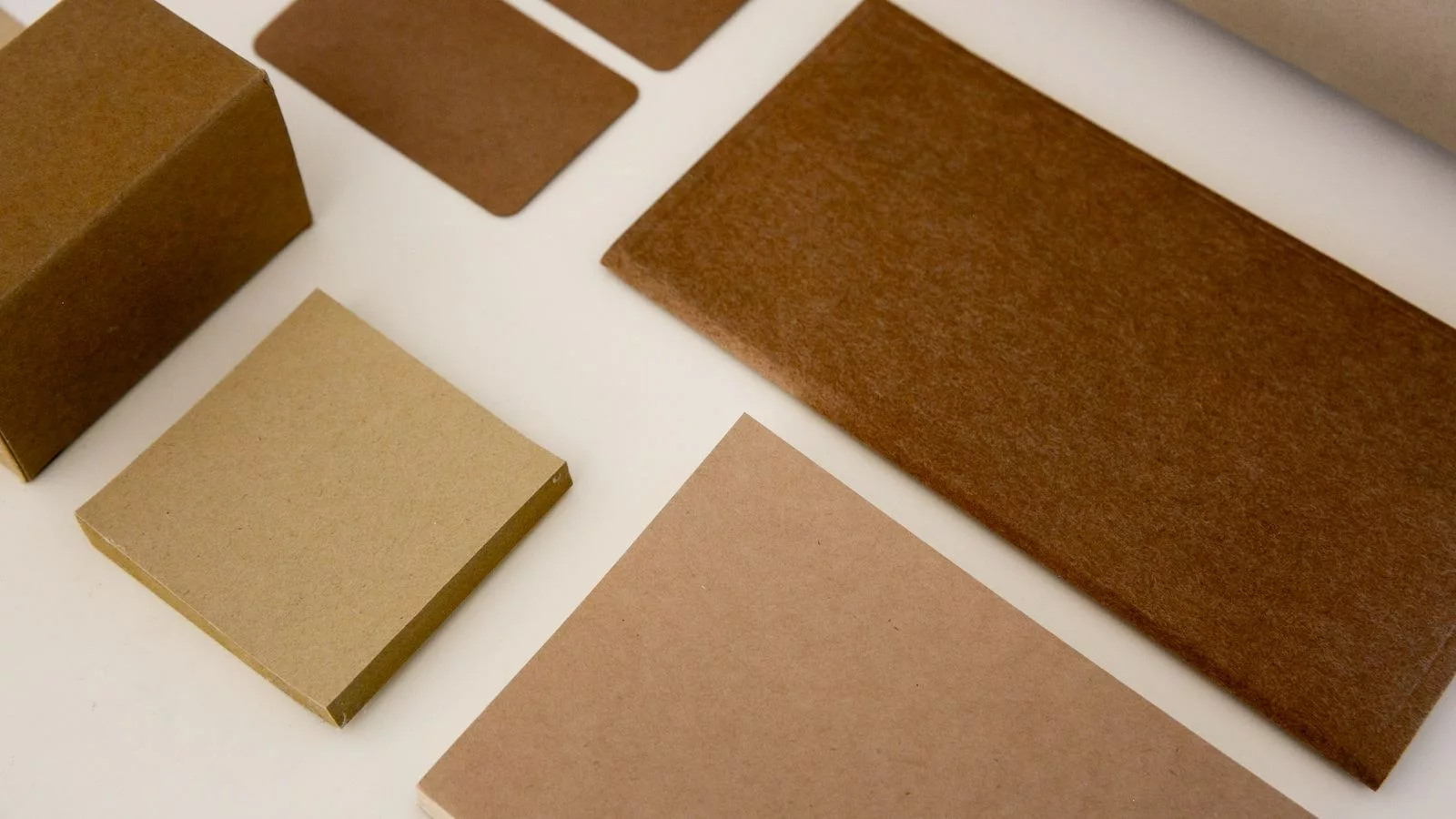 Matériel pour faire un sac en papier : feuilles kraft, ficelle, ciseaux et colle disposés sur une table