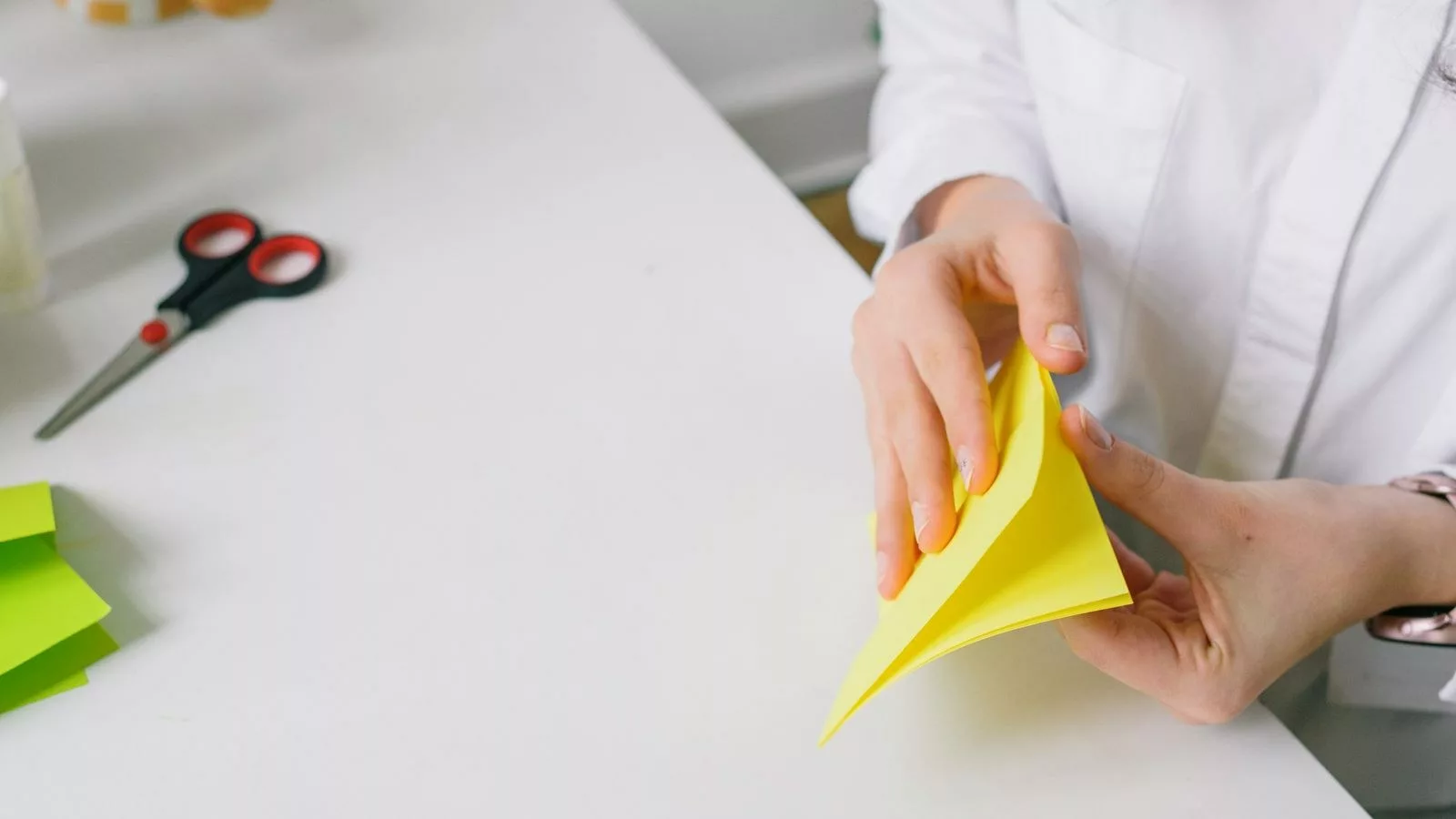 Mains pliant une feuille de papier kraft pour former les soufflets latéraux d'un sac