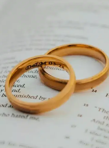Deux alliances en or dont une gravée d'initiales et d'une date posées sur un livre