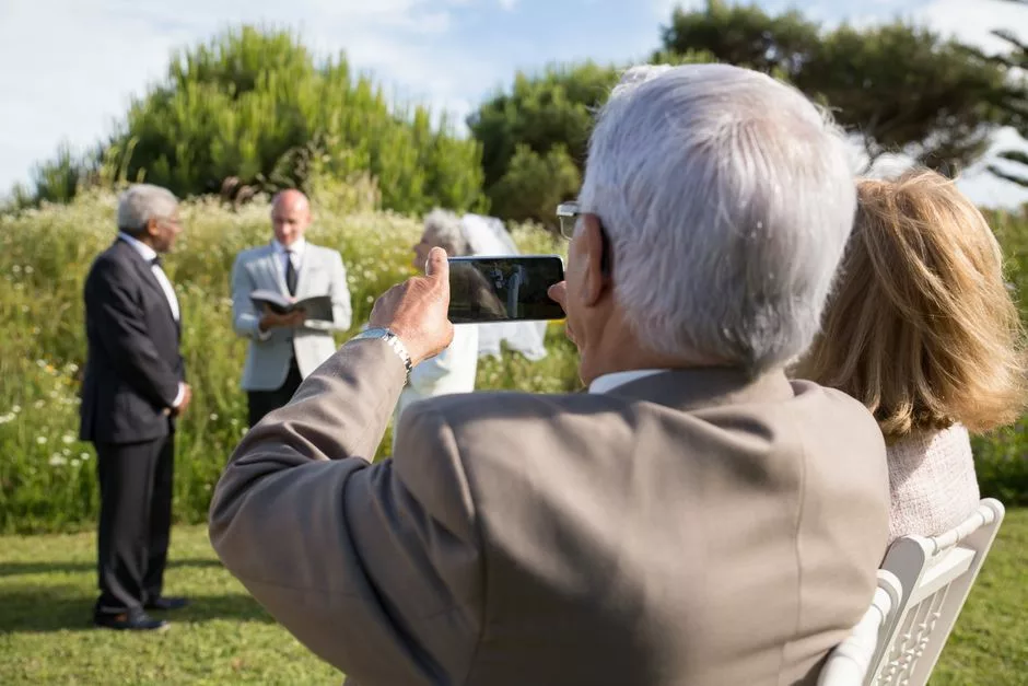 Invités prenant des photos avec leur smartphone lors d'une cérémonie de mariage