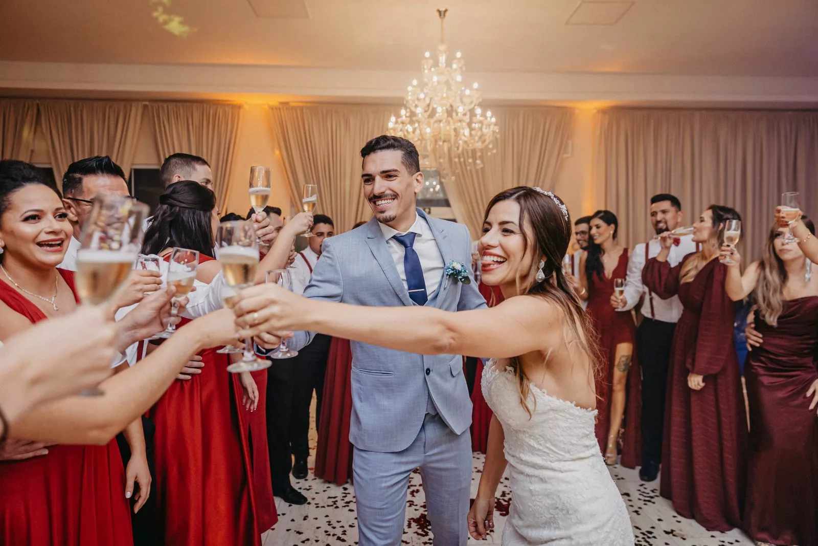 Mariés trinquant avec leurs invités au champagne dans une salle de réception