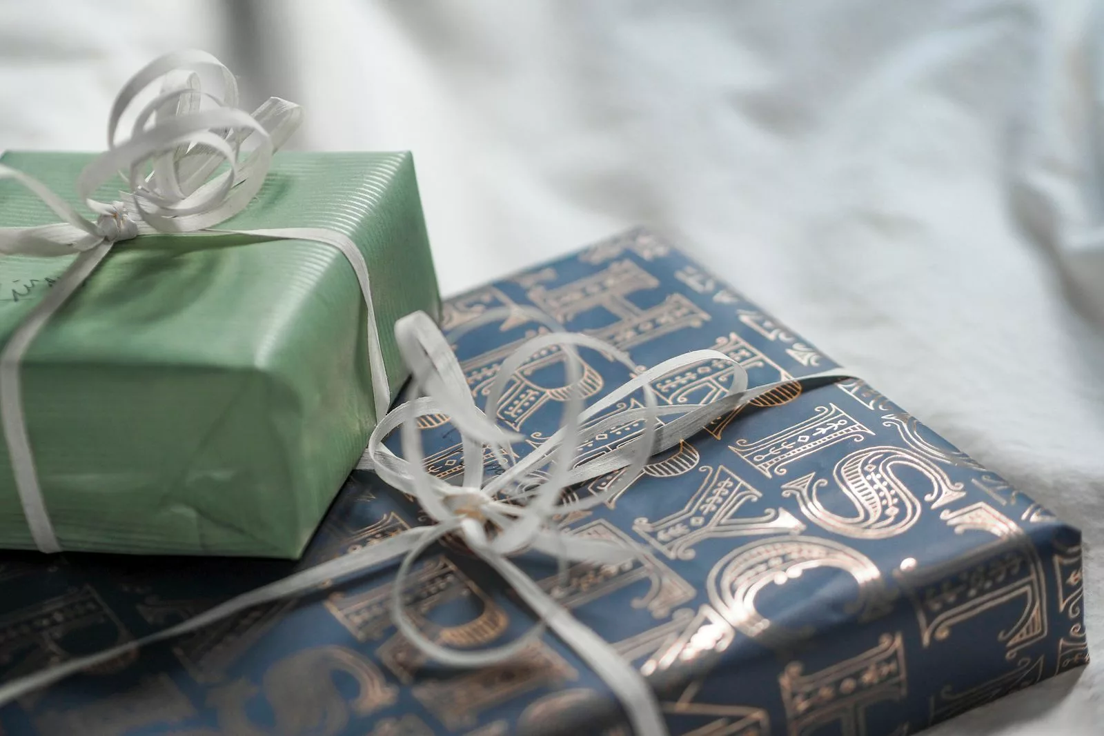 Deux cadeaux de mariage emballés dans des papiers vert sauge et bleu nuit dorés