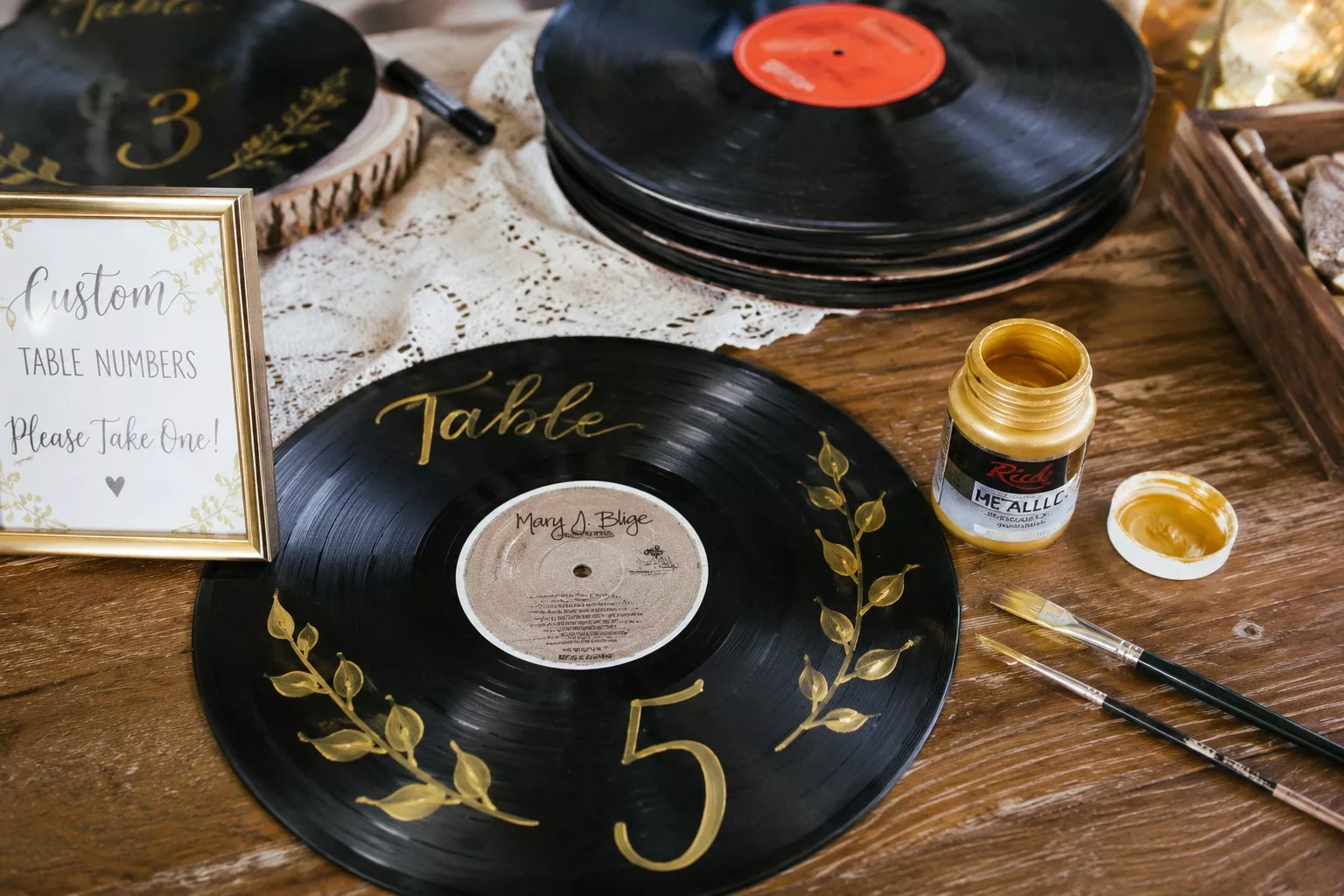 Matériel DIY pour un plan de table mariage musique : disques vinyles, peinture dorée et pinceaux