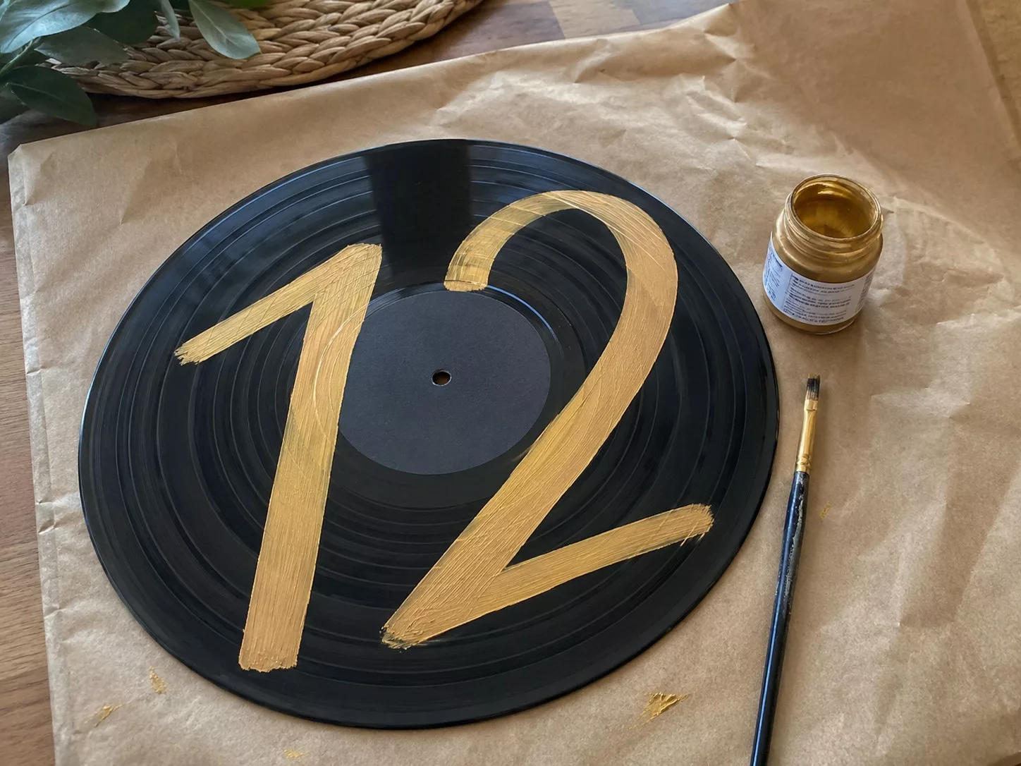 Disque vinyle avec un numéro doré peint à la main en train de sécher, DIY mariage musique