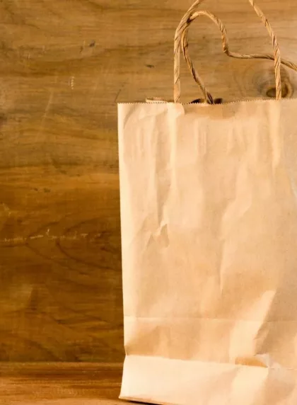 Sac en papier kraft fini avec anses en ficelle, posé sur une table en bois