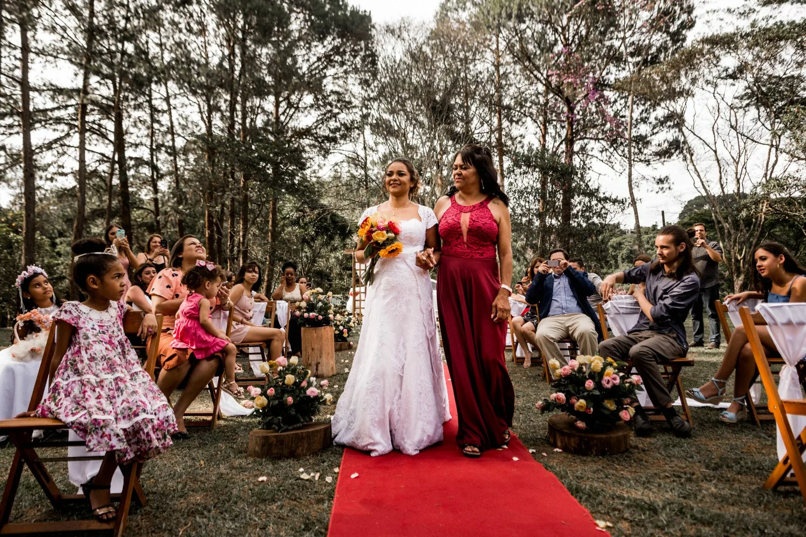 Procession lors d'une ceremonie de mariage en exterieur avec invitee en robe bordeaux
