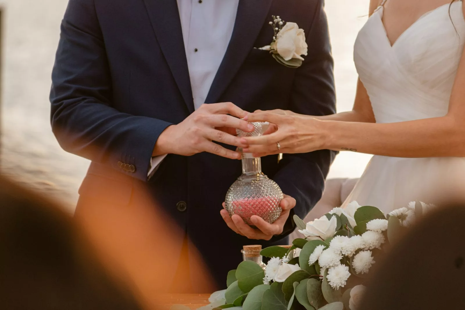 Mains d'un couple mélangeant deux sables de couleurs différentes lors d'un rituel du sable