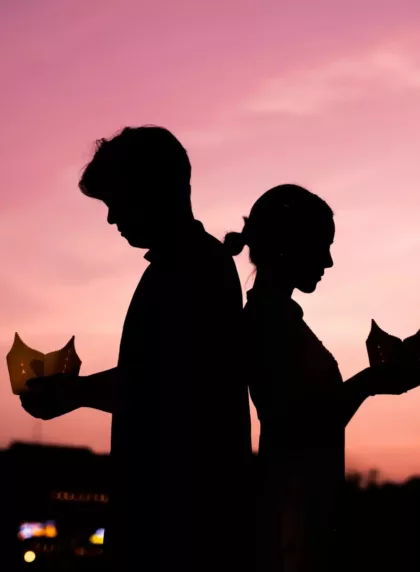 Silhouette de mariés tenant des lanternes en papier au coucher de soleil