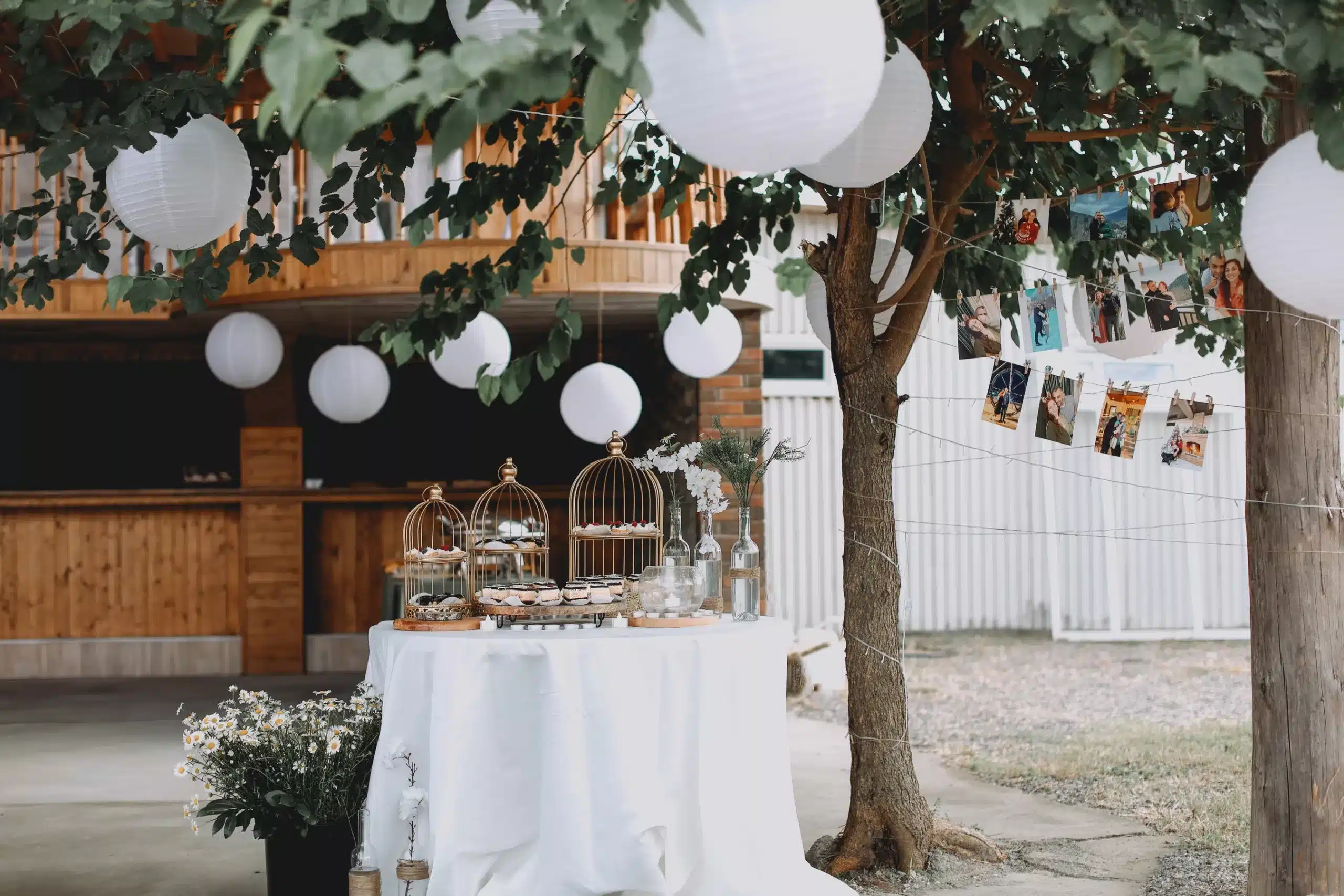 Lampions blancs suspendus dans un arbre au-dessus d'une table de mariage champêtre