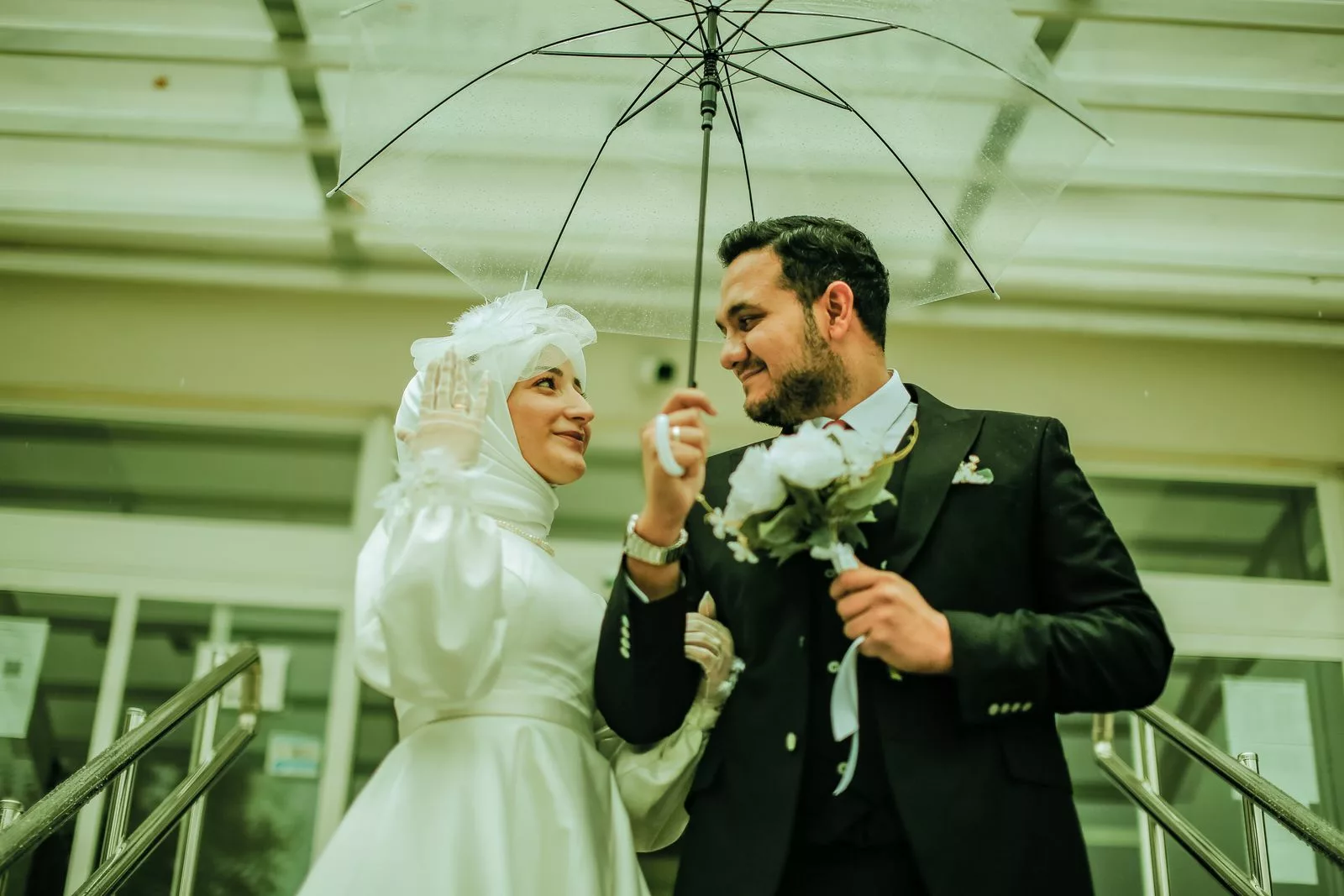 Mariés sous parapluie transparent avec bouquet blanc, danse du parapluie