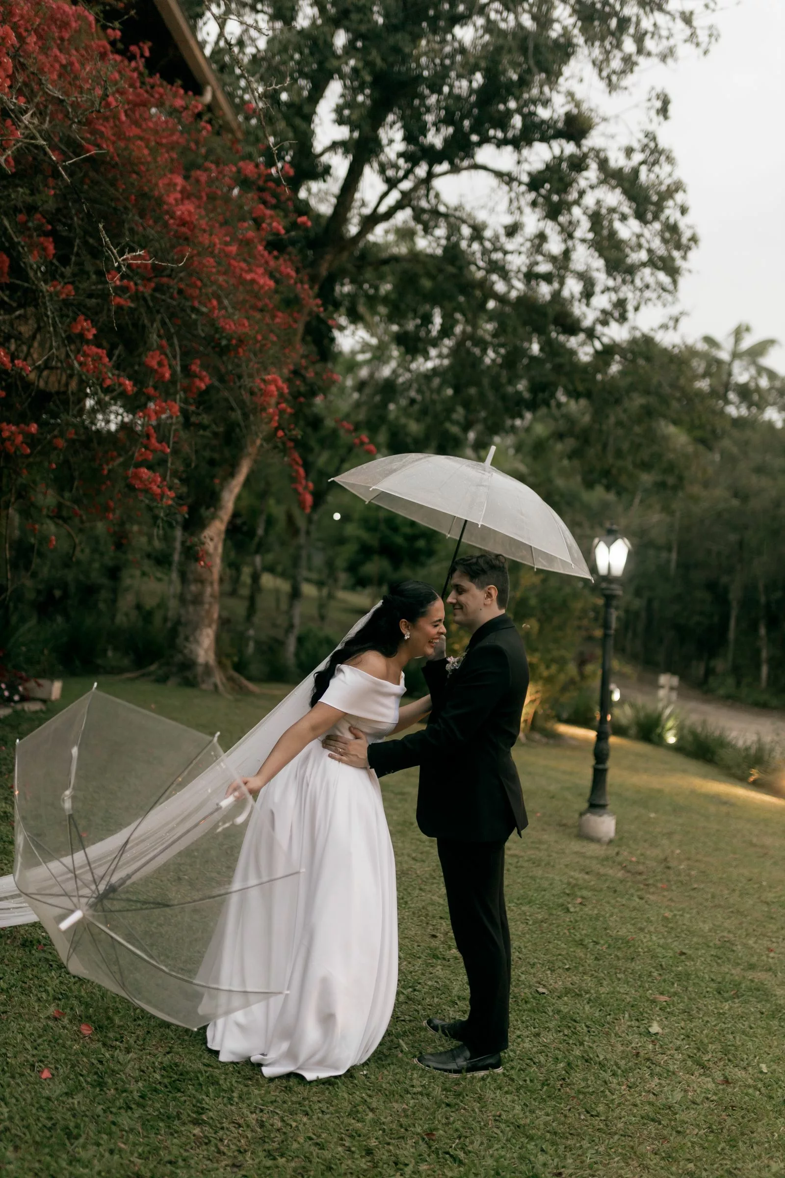 Couple sous parapluie transparent dans un jardin fleuri lors de la danse du parapluie