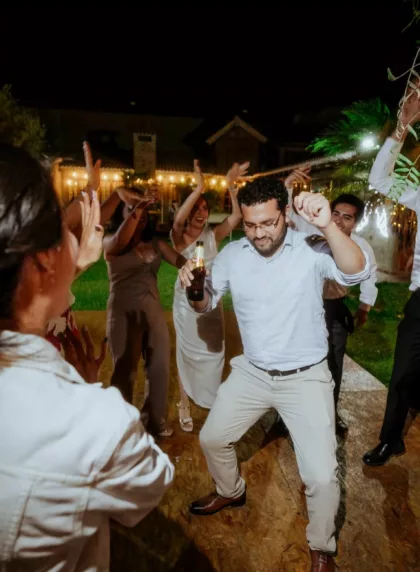 Invités et mariés dansant en cercle lors d'un flashmob de mariage en extérieur, sous les guirlandes lumineuses