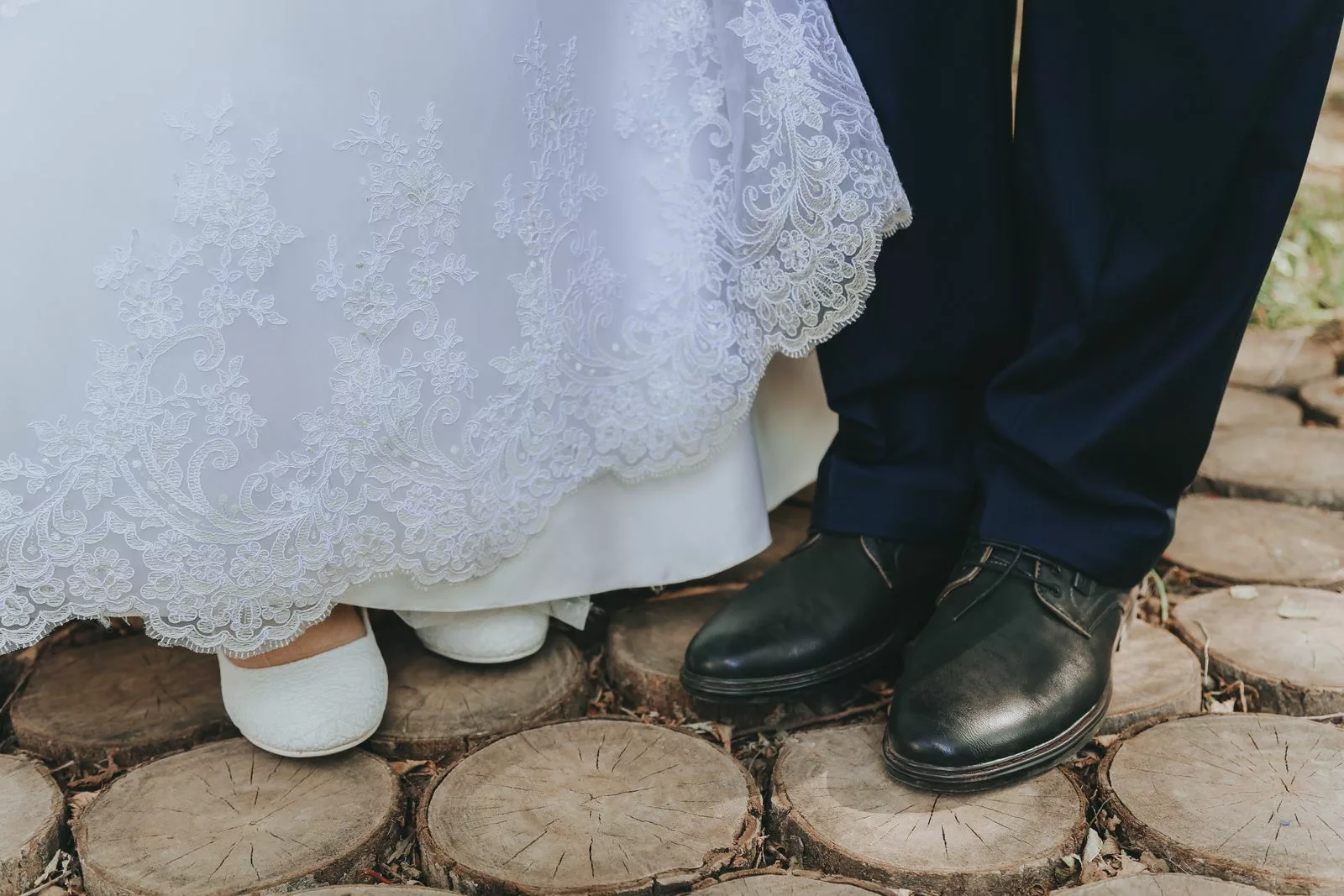 Chaussures blanches de la mariée et souliers noirs du marié posés sur des rondins de bois