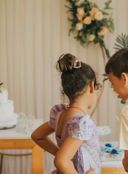 Deux enfants devant une table de mariage decoree avec un gateau et des arches florales
