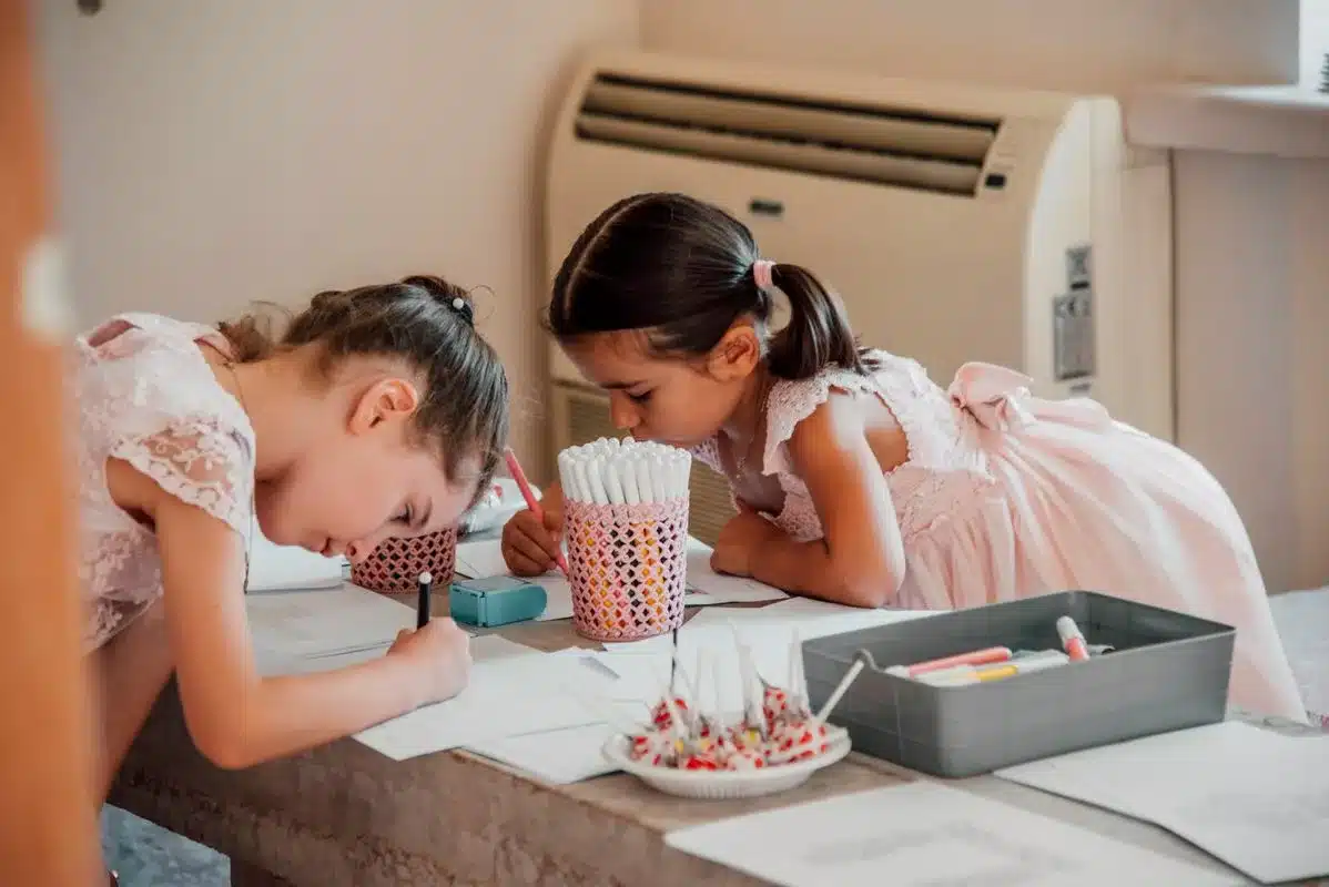 Deux petites filles en robes roses dessinent et colorient a une table pendant un mariage