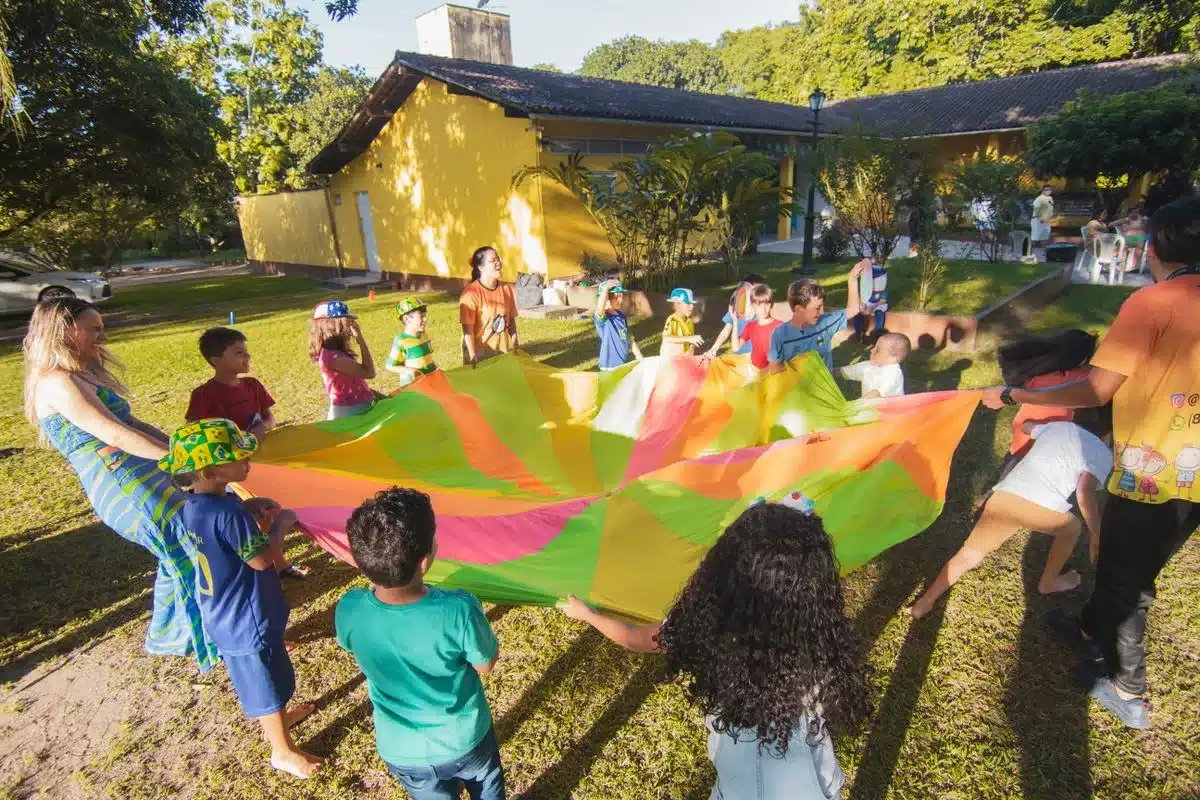 Groupe d enfants jouant au parachute multicolore en plein air pendant une reception