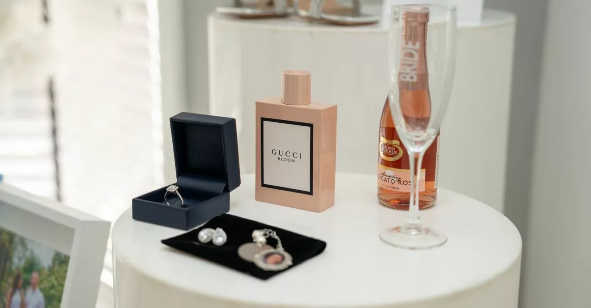 Accessoires de mariée élégants : parfum, bijoux et champagne sur guéridon blanc
