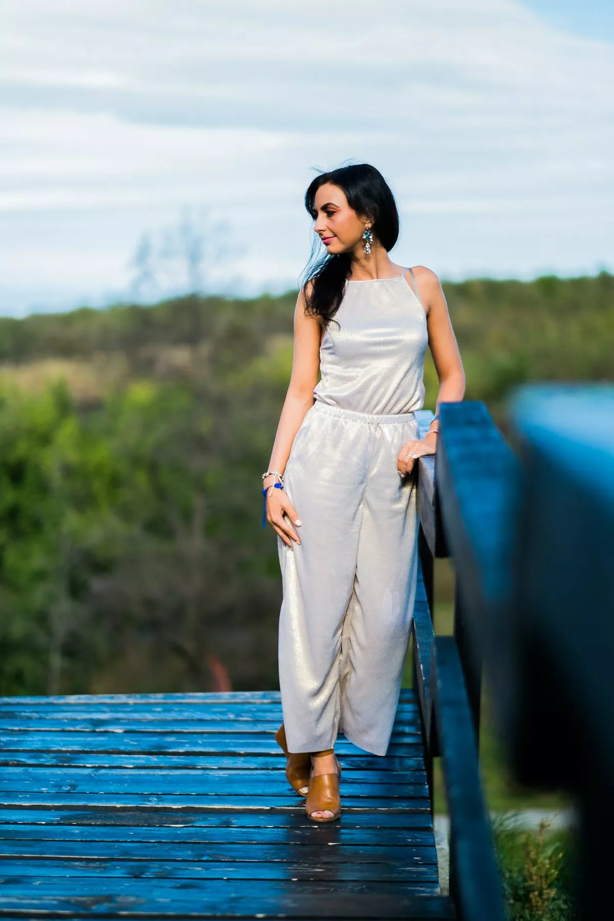 Jeune invitée en combinaison pantalon fluide beige doré sur une passerelle en bois