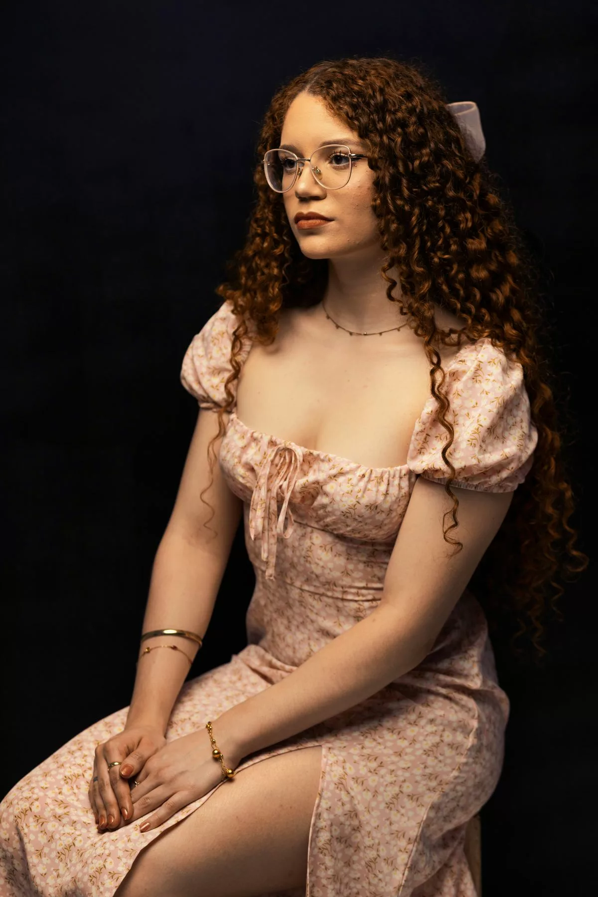 Jeune invitée en robe midi fleurie à manches ballon rose poudré, assise élégamment