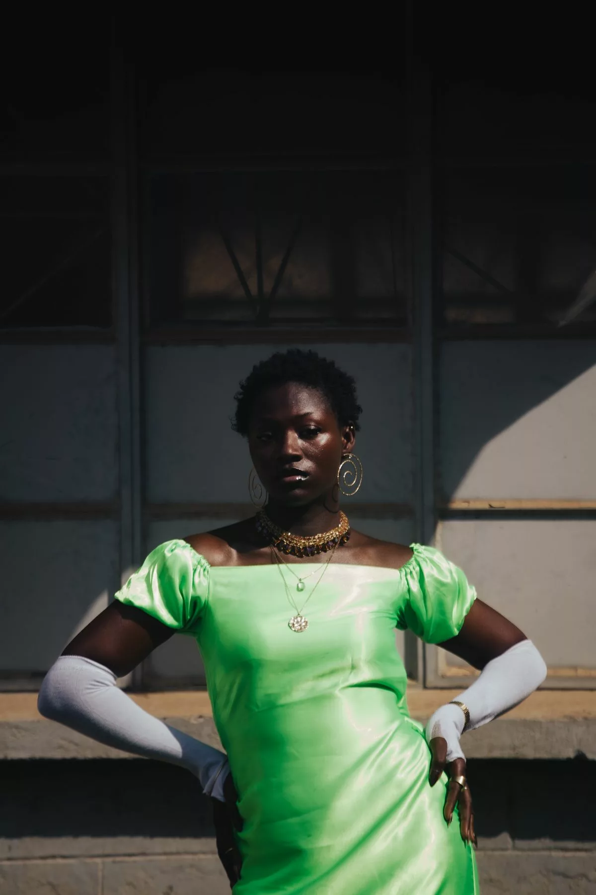 Jeune invitée en robe satin vert vif à manches ballon et bijoux dorés